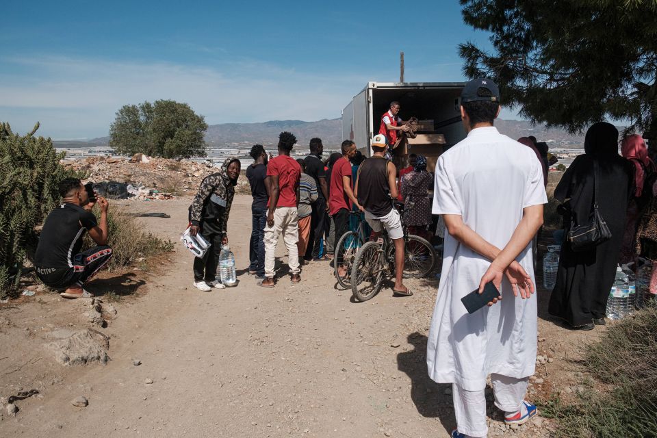 Migrantische Arbeiter:innen warten vor einem Lastwagen auf Hilfsgüter