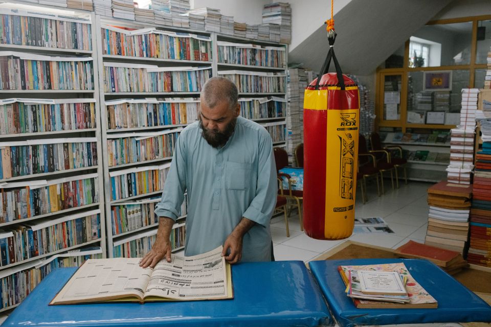 Ahmad Schah Wahdat steht an einem Tisch im Keller und liest in einer alten Zeitung
