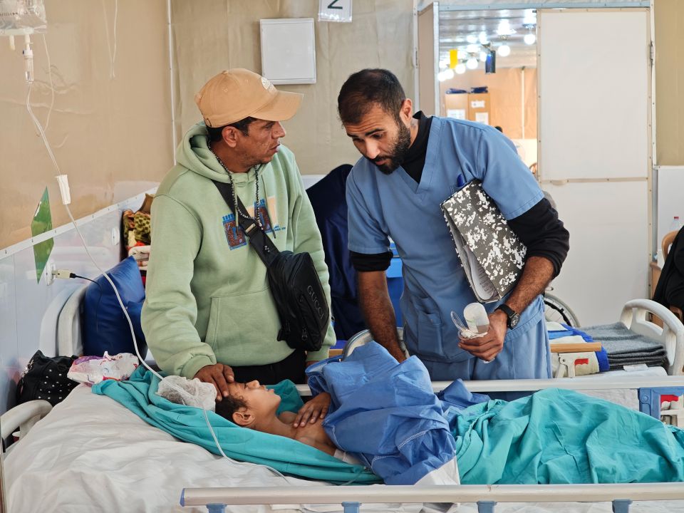 ein Arzt spricht mit Muhammad Abu Said und seiner Tochter Kinsi, welche in einem Spitalbett liegt