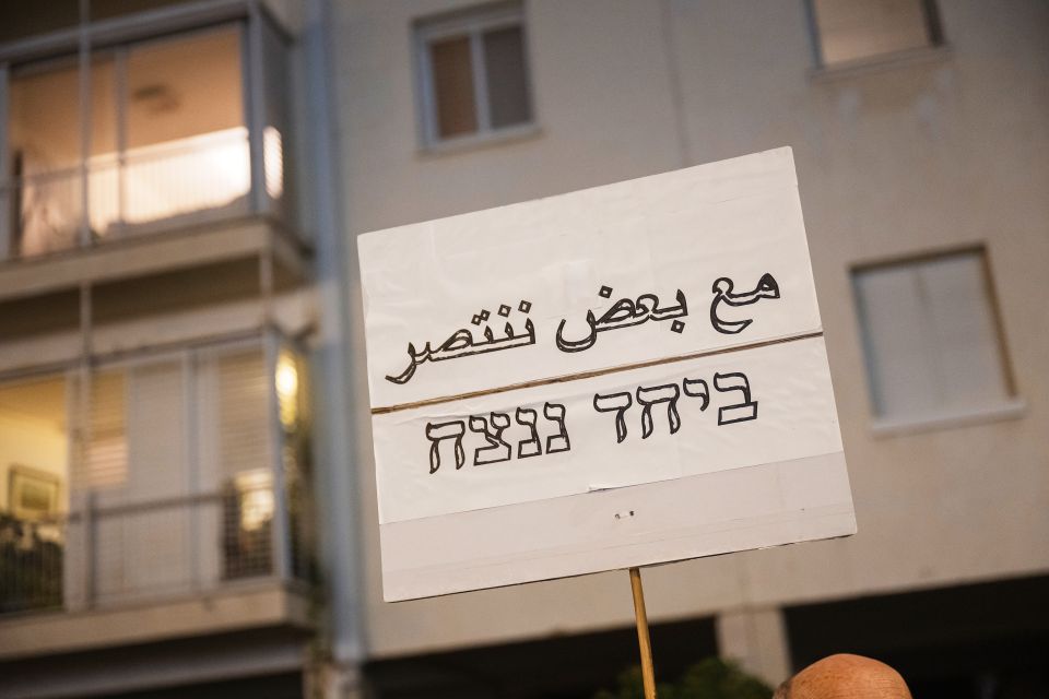 ein Schild auf dem auf Arabisch und Hebräisch «Zusammen werden wir gewinnen» steht