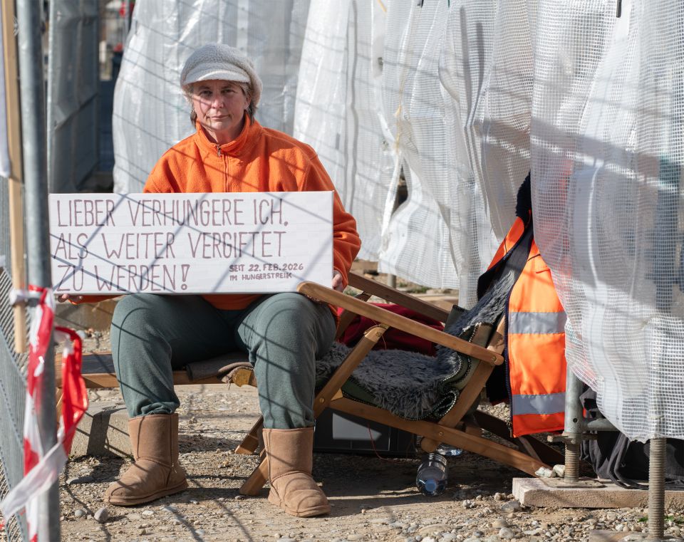 Silvia Horrer zeigt ein Schild mit der Aufschrift «LIEBER VERHUNGERE ICH. ALS WEITER VERGIFTET ZU WERDEN! SEIT 22. FЕB. 2026 IM HUNGERSTREIK»