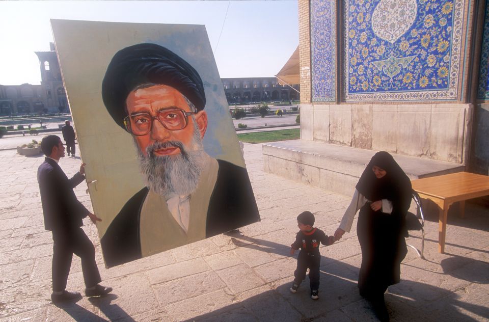 eine Person hält ein grosses Porträt-Bild von Ali Chamenei