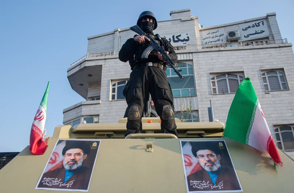 ein Soldat mit Gewehr steht auf einem gepanzerten Fahrzeug auf dem das Konterfei des neuen Obersten Führers Modschtaba Chamenei angebracht ist