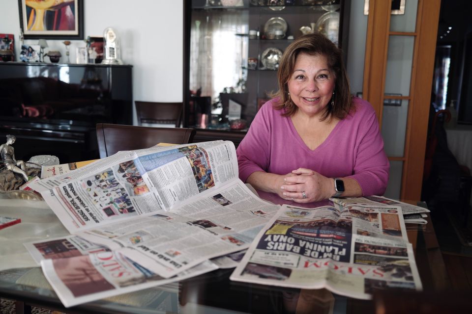 Karen Şarhon sitzt am Tisch und zeigt ihre Monatszeitung «El Amaneser»