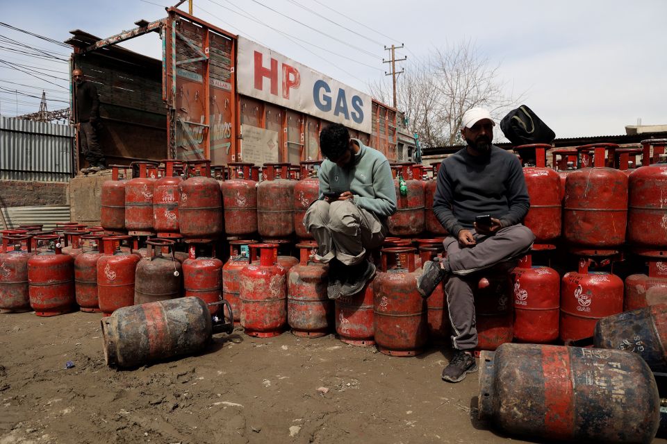 zwei Männer sitzten bei einem Lager mit leeren Gasflaschen