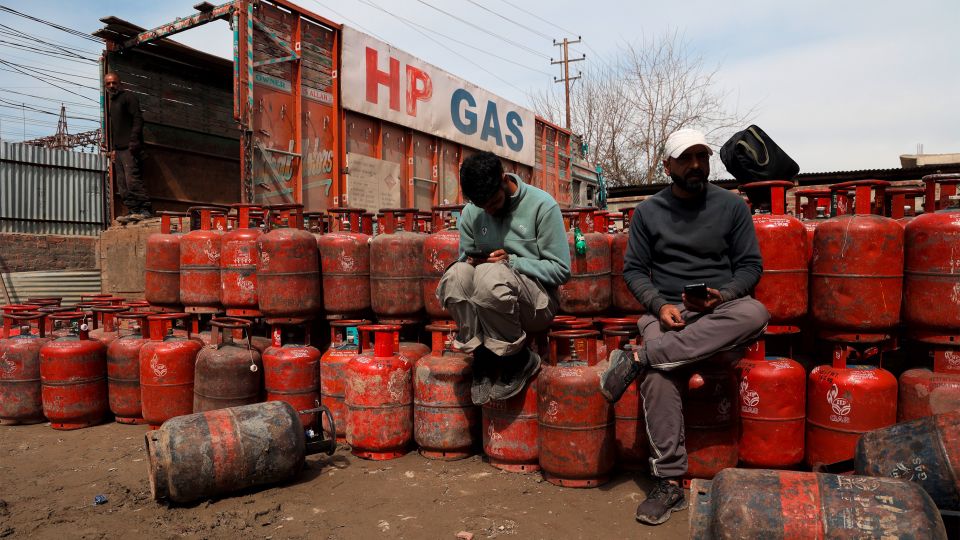 zwei Männer sitzten bei einem Lager mit leeren Gasflaschen