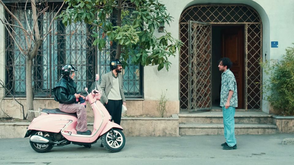 Filmstill aus «Divine Comedy»: zwei Personen auf einer Vespa unterhalten sich mit einer weiteren Person