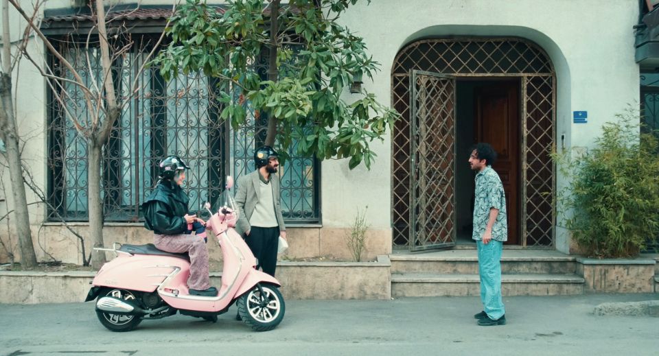 Filmstill aus «Divine Comedy»: zwei Personen auf einer Vespa unterhalten sich mit einer weiteren Person