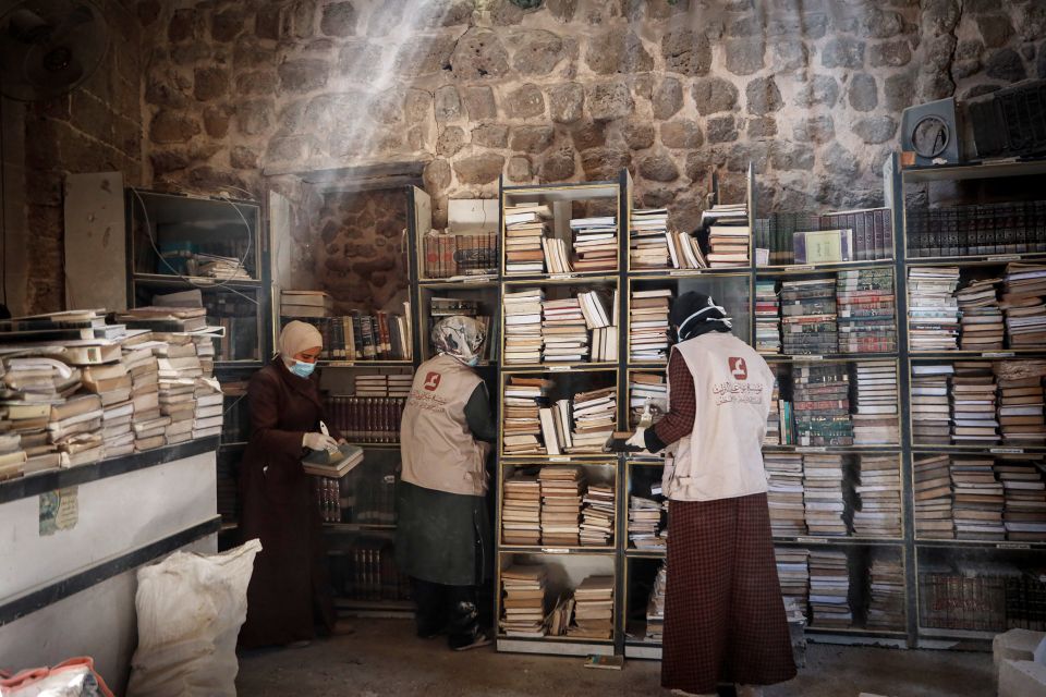 drei Frauen reinigen und sortieren Bücher in der Omari-Bibliothek in Gaza-Stadt