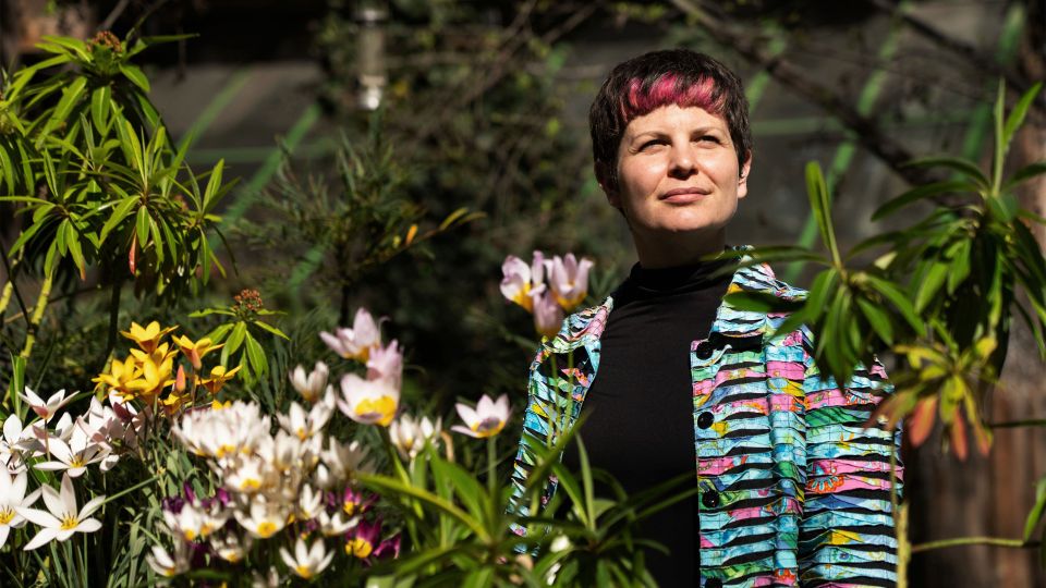 Zoë Garbett steht im einem Garten mit Blumen