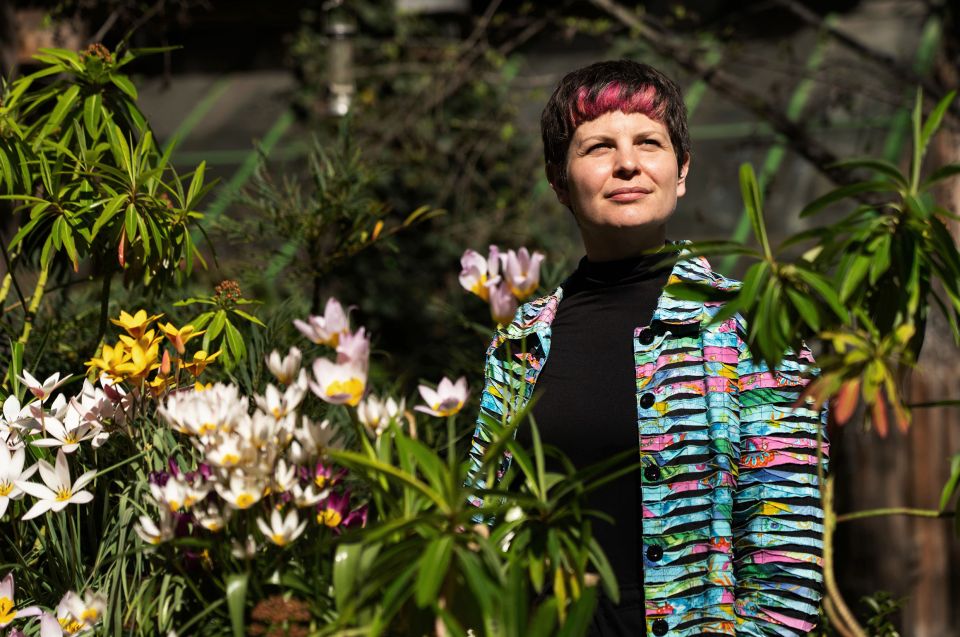 Zoë Garbett steht im einem Garten mit Blumen
