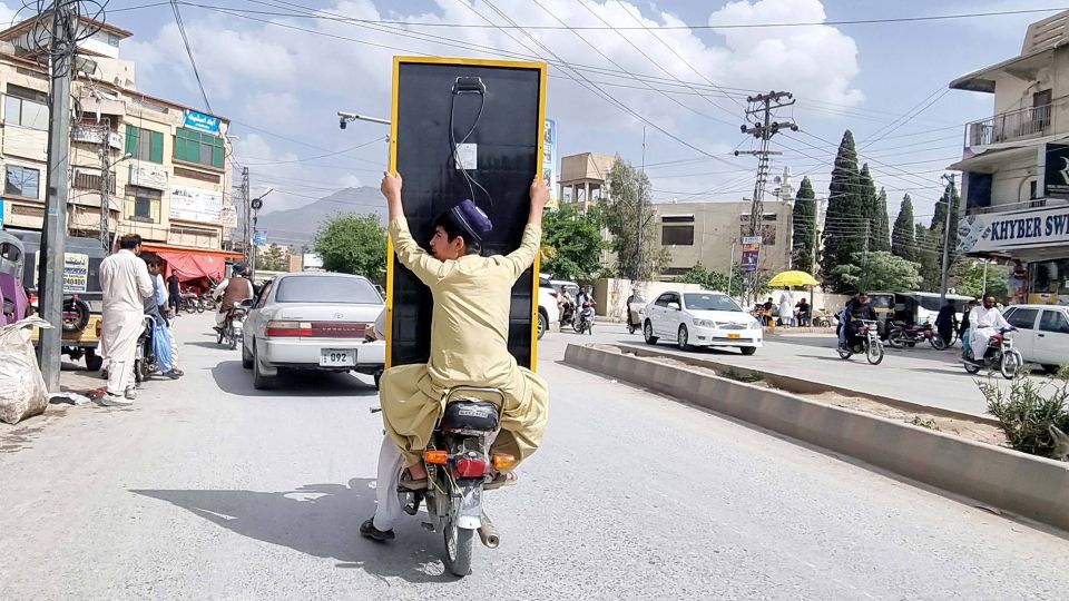 Motorradfahrer transportieren ein Solarpanel durch die Stadt Quetta