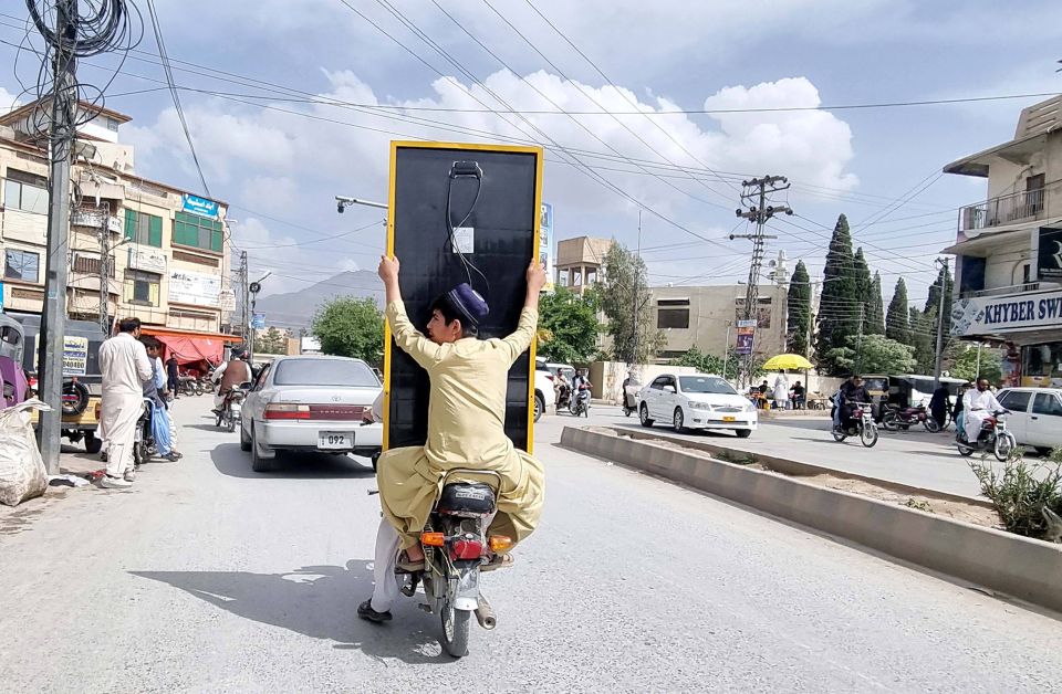 Motorradfahrer transportieren ein Solarpanel durch die Stadt Quetta