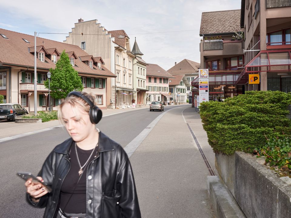 eine junge Person mit Kopfhörern läuft auf einem Gehweg in Huttwil