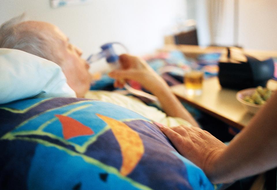 Symbolbild: eine pflegebedürftige Person liegt auf einem Bett