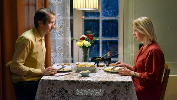 Filmstill aus «Fallen Leaves»: Eine Frau und ein Mann sitzen sich beim Essen an einem Tisch gegenüber