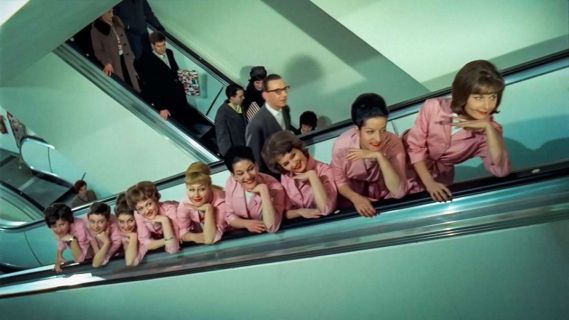 Filmstill aus «Jelmoli. Biografie eines Warenhauses»: Frauen in Uniform auf der Rolltreppe