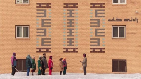 Filmstill aus «Universal Language»: Mehrere Personen stehen vor einem Gebäude