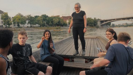 Filmstill aus «Barbara Buser. Pionierin der Nachhaltigkeit»: Barbara Buser mit Jugendlichen auf einer Flussfähre